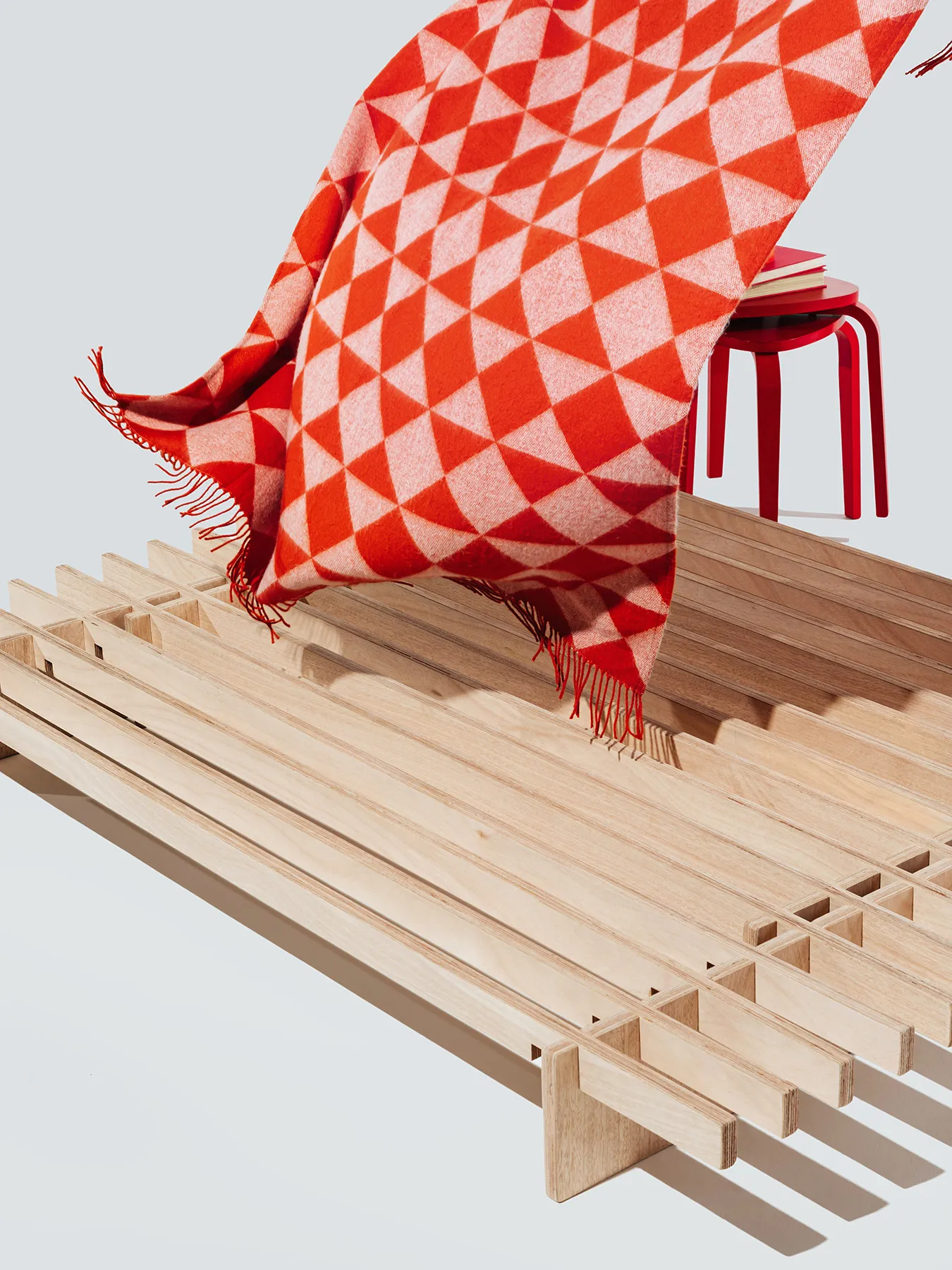 A red patterned blanket floating over top of the No Fuss Plus bed frame by Quagga Designs.