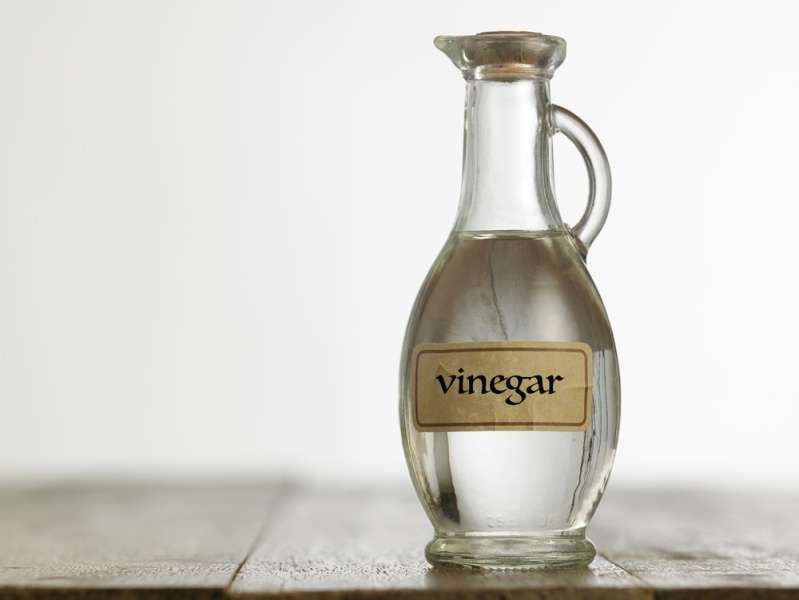 A bottle of vinegar in a glass bottle on a wooden table.