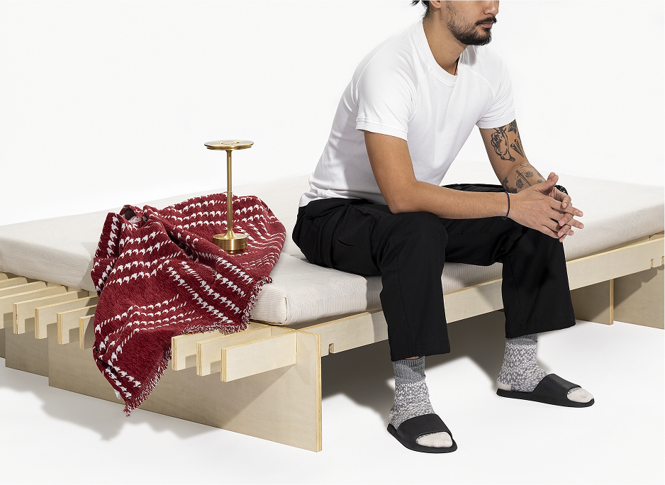 A person sitting on the No Fuss Plus bed frame by Quagga Designs.