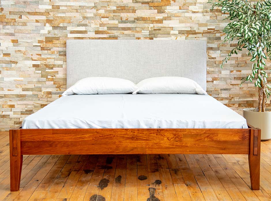 A Rustic bed frame with mattress, pillows, and headboard.