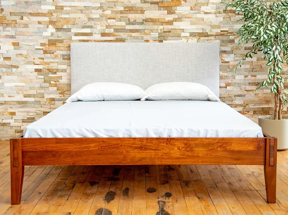 A Rustic bed frame with mattress, pillows, and headboard.